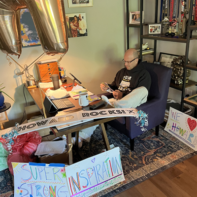 Howard Aaron sits behind his desk in his home office, surrounded by balloons and posters that display phrases like “Super Strong” and “Inspiration.” 